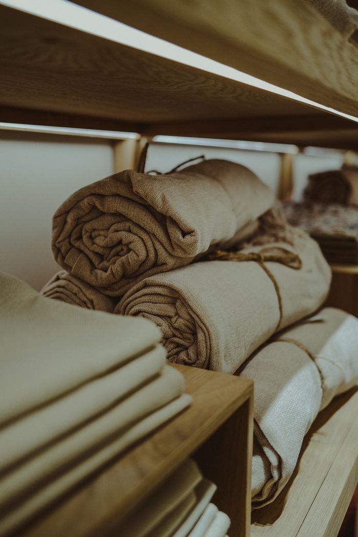 Various fabric rolls stacked in a textile store, showcasing diverse colors and textures.