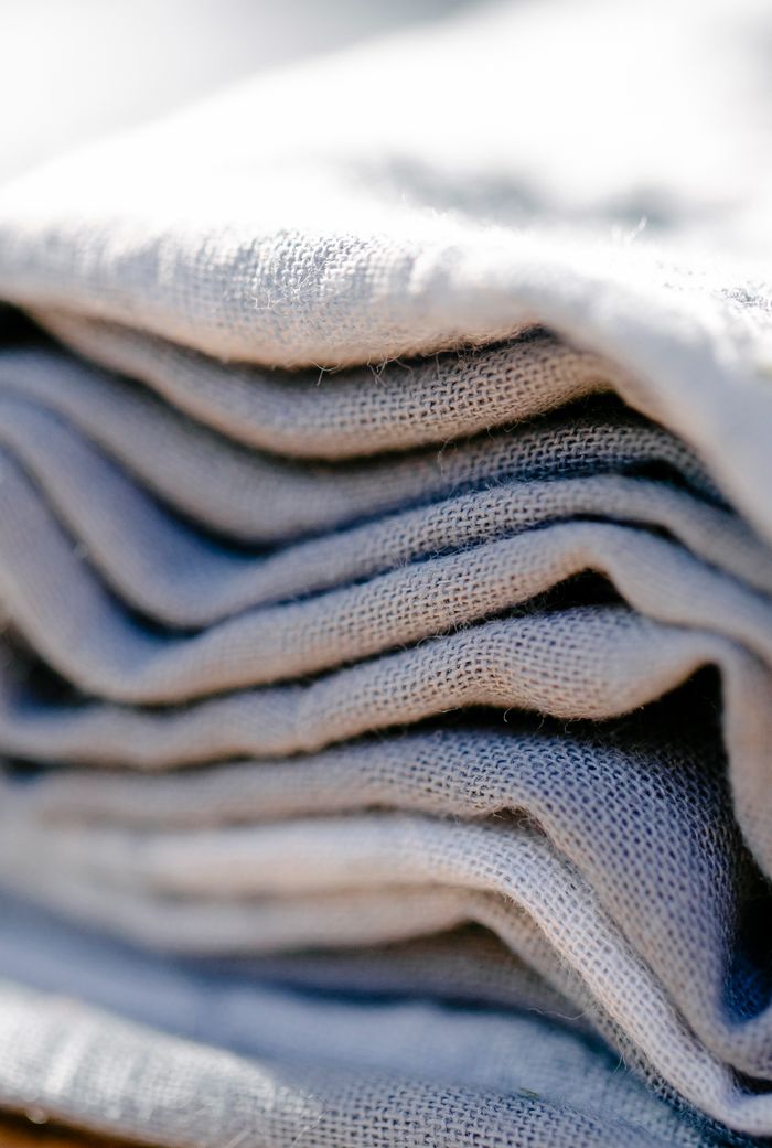 Closeup various layers of rolled linen textile stacked and placed against blurred background under bright sunlight during production of natural cloth